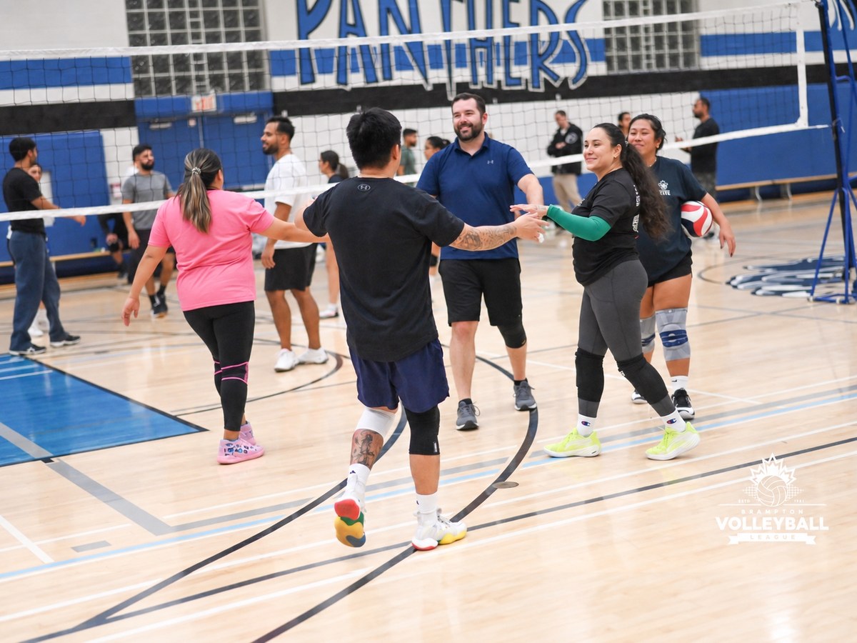 Volleyball players greeting teammates on an indoor court.